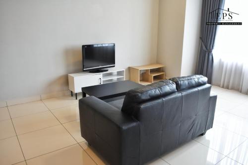 a living room with a black leather couch and a tv at DaMen Homestay @SubangHomeStay in Subang Jaya