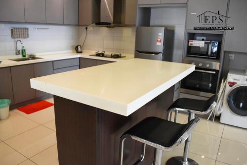 a kitchen with a white counter and two bar stools at DaMen Homestay @SubangHomeStay in Subang Jaya