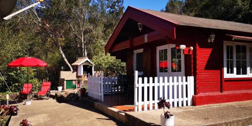una casa rossa con una recinzione bianca e sedie rosse di Casa Rural La Gustoza a El Sauzal