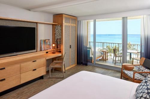 a bedroom with a bed and a television and a balcony at Turtle Bay Resort in Kahuku