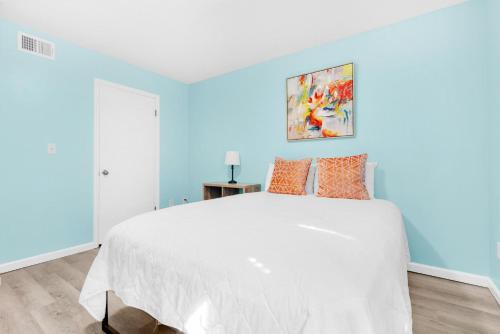 a bedroom with a white bed and a blue wall at Sand Castles West II G6- NEW in Panama City Beach