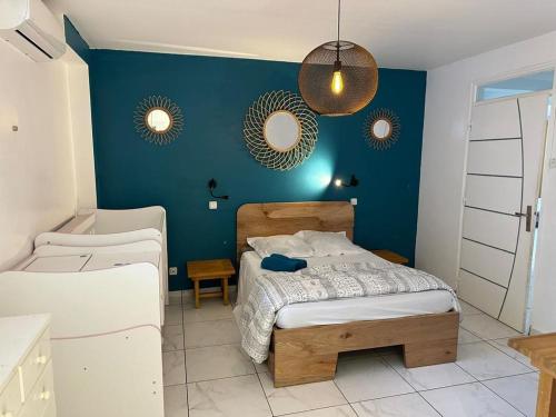 ein Schlafzimmer mit einem Bett und einer blauen Wand in der Unterkunft Villa 3 grandes chambres . in Sainte-Anne