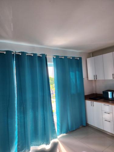 een keuken met blauwe gordijnen voor een raam bij Blue Pool Sol Caribe in Punta Cana
