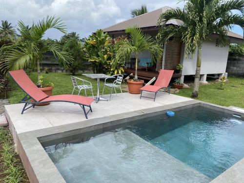 een zwembad met 2 stoelen en een tafel en stoelen bij TAHITI - Bungalow Toah Hoe in Taravao