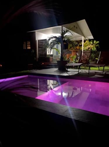 Taravao的住宿－TAHITI - Bungalow Toah Toru，游泳池晚上有紫色灯光