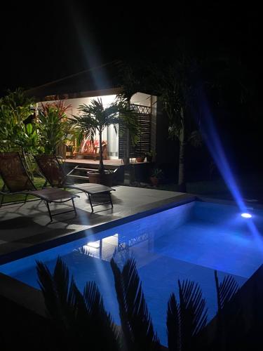 a pool at night with two chairs and a table at TAHITI - Bungalow Toah Piti in Taravao