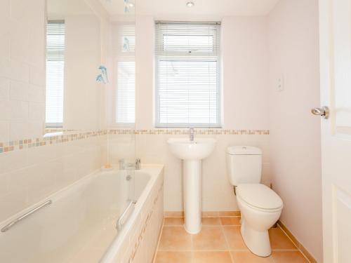 a bathroom with a tub and a toilet and a sink at Heath Lodge in Brixham