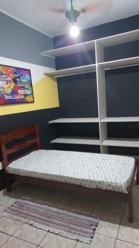 a bed in a room with a wall with shelves at Quarto individual masculino in Sao Jose do Rio Preto