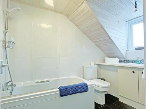 a white bathroom with a toilet and a shower at Cockleshell Cottage in Millom