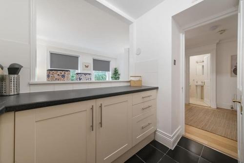 eine Küche mit weißen Schränken und einer schwarzen Arbeitsplatte in der Unterkunft Knightsbridge Two Bed Apartment in London