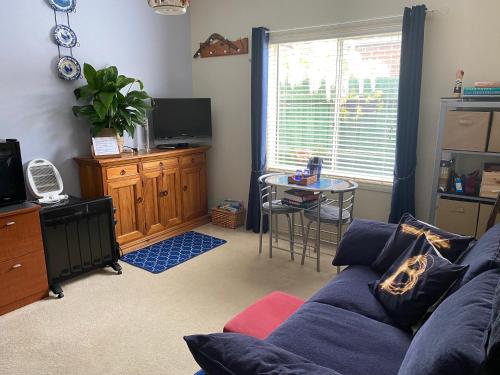 a living room with a blue couch and a table at We Love the Bay short stays private suite 1 to 4 days in Saint Leonards