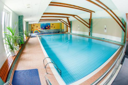 
a swimming pool with a swimming pool tub and chairs at Hotel Patria in Štrbské Pleso
