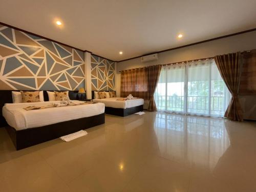 a bedroom with two beds and a large window at Lanta Arrow House in Ko Lanta