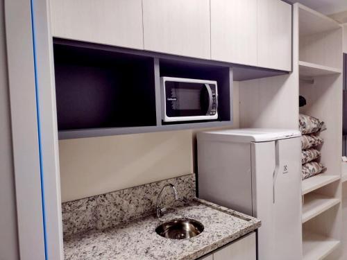 una pequeña cocina con fregadero y microondas en APARTAMENTO SPAZZIO DI ROMA com acesso ao acqua park splash, en Caldas Novas