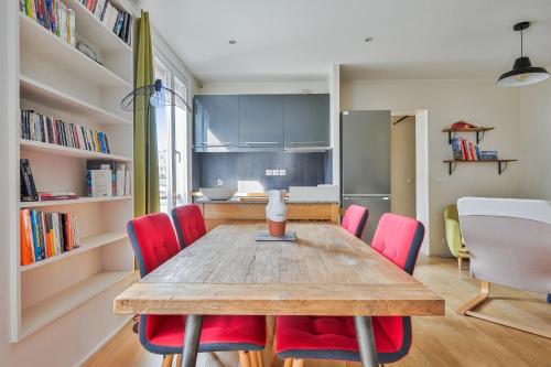 une salle à manger avec une table en bois et des chaises rouges dans l'établissement Appartement Charenton - Welkeys, à Paris