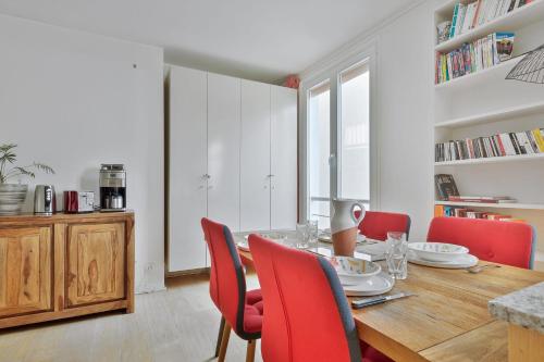 une salle à manger avec une table en bois et des chaises rouges dans l'établissement Appartement Charenton - Welkeys, à Paris