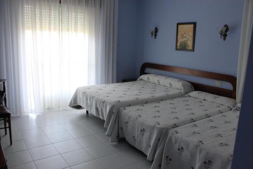 a bedroom with two beds and a window at Hotel Arco Iris in Villanueva de Arosa