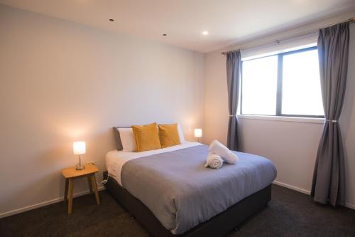 a bedroom with a bed with yellow pillows and a window at Skyrim Lodge in Lake Tekapo