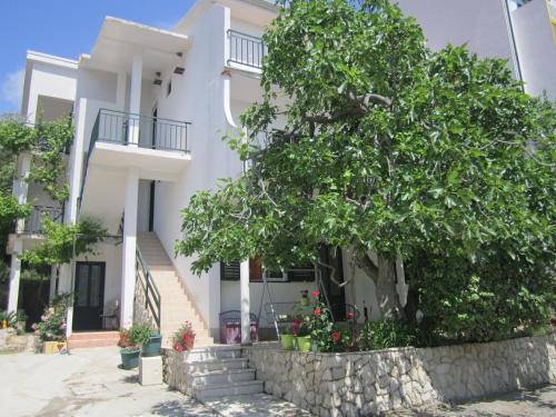 uma casa branca com uma árvore em frente em Apartments Andrea em Drvenik