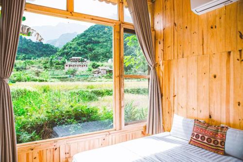 Schlafzimmer mit einem Fenster mit Blick auf ein Feld in der Unterkunft Chien's Lodge Du Gia in Làng Cac