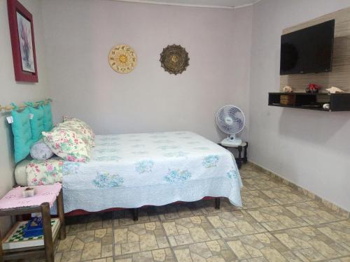 a bedroom with a bed and a fan and a tv at Kitnet da Elô in Tramandaí
