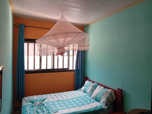 a bedroom with a bed and a window with a chandelier at RÉSIDENCE TCHAMS in Yaoundé