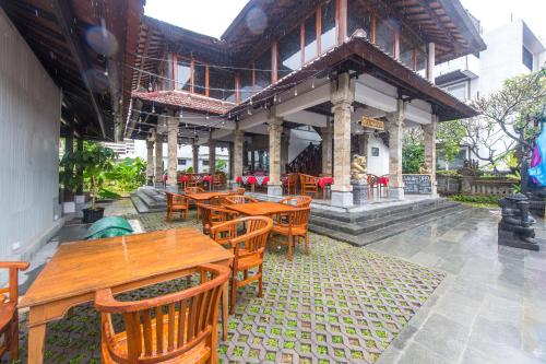 um restaurante ao ar livre com mesas e cadeiras de madeira em Hotel Sari Bunga em Legian