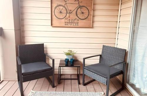 two chairs and a table on a porch with a bike on the wall at Cozy Lakeside Getaway - Outdoor Theater - Free Early Check-In- 4min to Silver Dollar City in Branson