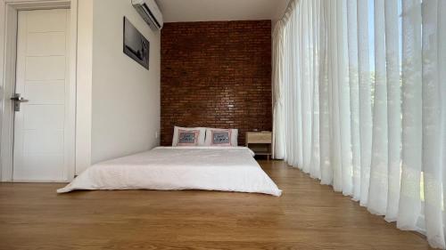 a bedroom with a bed and a brick wall at Huyen's Home in Ba Ria