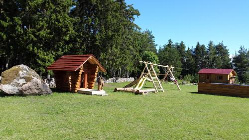 a playground with a log cabin and a swing at Männiste Holiday Home in Hiievälja
