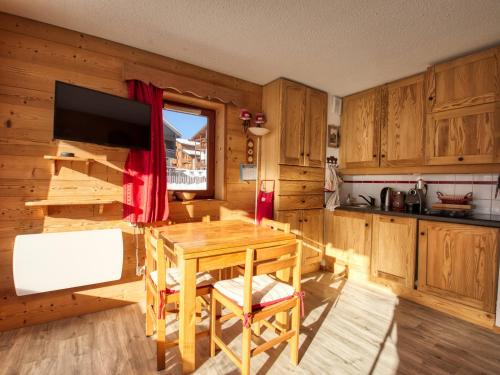 une cuisine avec des placards en bois, une table et une télévision dans l'établissement Appartement lumineux au pied des pistes, terrasse sud, 2 chambres - FR-1-642-84, à Morillon