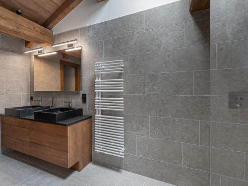 La salle de bains est pourvue d'un comptoir, d'un lavabo et d'un mur. dans l'établissement Chalet de luxe à 2 pas des pistes avec piscine, sauna et salle de sport - FR-1-569-134, à Megève