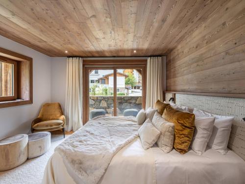 une chambre avec un grand lit avec un plafond en bois dans l'établissement Chalet de luxe à 2 pas des pistes avec piscine, sauna et salle de sport - FR-1-569-134, à Megève