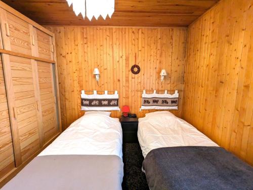 two beds in a small room with wooden walls at Appartement La Clusaz, 2 pièces, 4 personnes - FR-1-459-215 in La Clusaz