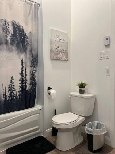 a bathroom with a toilet and a shower curtain at Le St-Augustin - à 15 minutes des Outlets de Mirabel in Mirabel