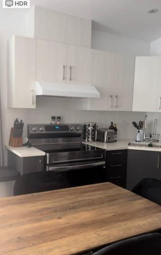 a kitchen with white cabinets and a wooden table at Le St-Augustin - à 15 minutes des Outlets de Mirabel in Mirabel