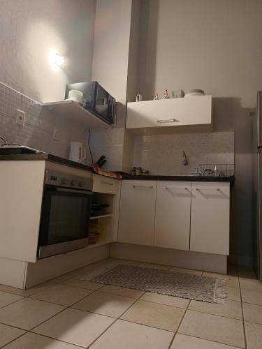 a kitchen with white cabinets and a stove top oven at Los naranjos in San Lorenzo