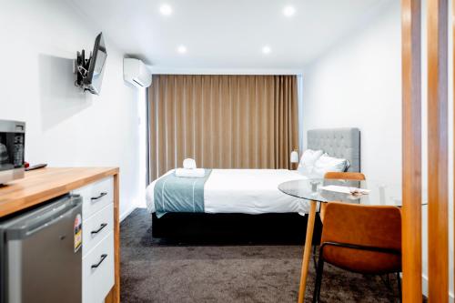 a hotel room with a bed and a table at Merivale Court Motel & Apartments in Christchurch