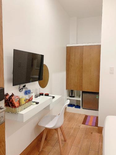 a white kitchen with a white chair and a tv at Lagi Sunrise Hotel in La Gi