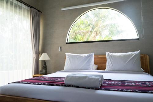 a bedroom with a large bed with a window at Mandevilla Canggu in Canggu