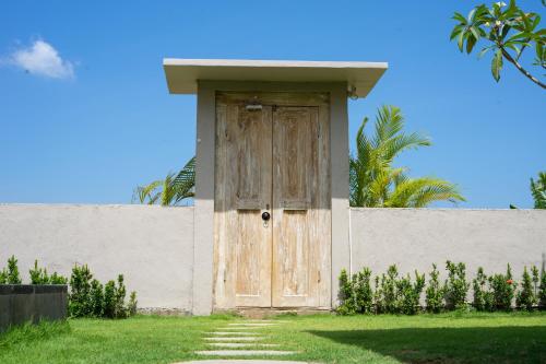 a wooden door on the side of a wall at Mandevilla Canggu in Canggu