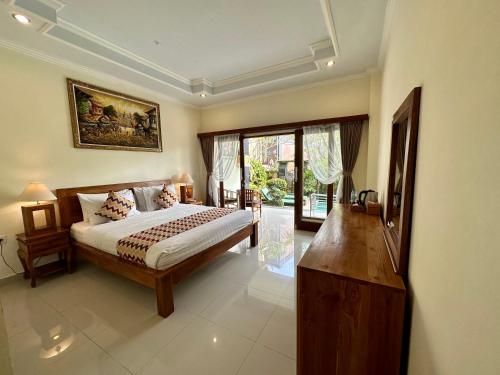 a bedroom with a bed and a large window at Saputra Guesthouse in Ubud