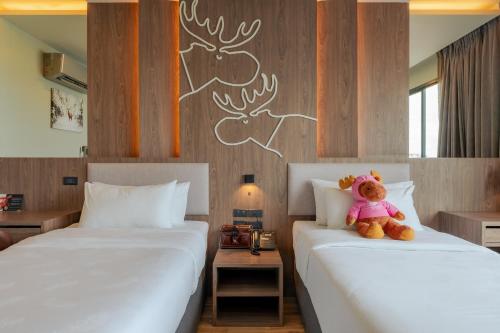 a teddy bear sitting on two beds in a room at Moose Hotel Chiangmai in Chiang Mai
