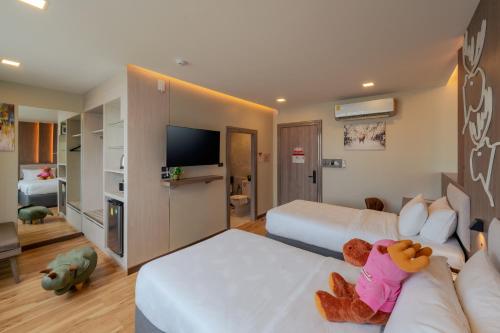 a hotel room with two beds and a tv at Moose Hotel Chiangmai in Chiang Mai