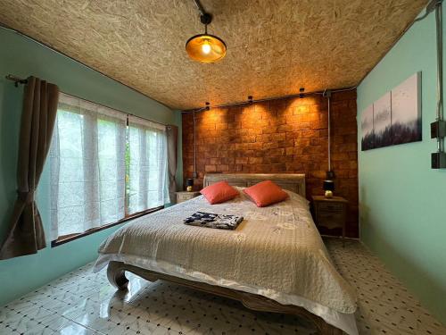 a bedroom with a bed and a brick wall at SukhothaiNeeDee FarmCafe in Sukhothai