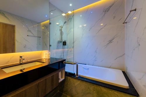 ein Bad mit einer Badewanne, einem Waschbecken und einer Dusche in der Unterkunft Moose Hotel Chiangmai in Chiang Mai