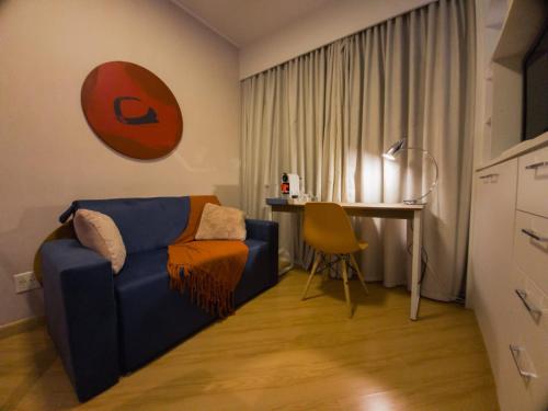 a living room with a blue couch and a desk at The Best Deluxe - Duplex Studio - Hotel Slav Moema - by LuXXoR in Sao Paulo