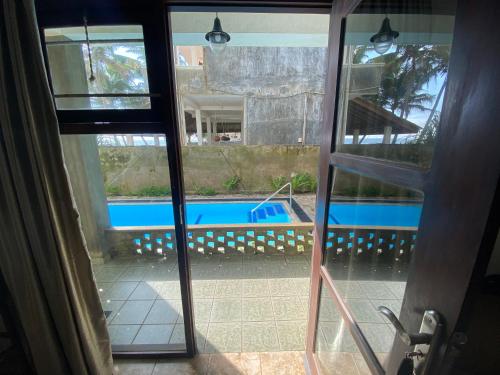 a view of a swimming pool from a glass door at Mirage Beach House at Morava Court in Hikkaduwa