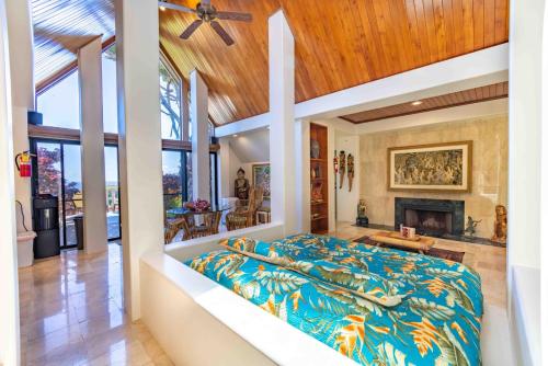 1 dormitorio con 1 cama grande y chimenea en Lavish Cliff House with Ocean Views in Haiku, Maui jungle en Huelo