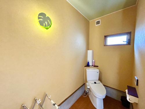 a bathroom with a toilet with a green sign on the wall at Beach Villa Tachibana in Onomichi